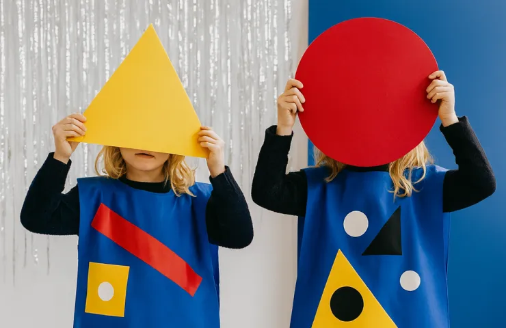 Dos niñas tapándose la cara con un triángulo y un círculo